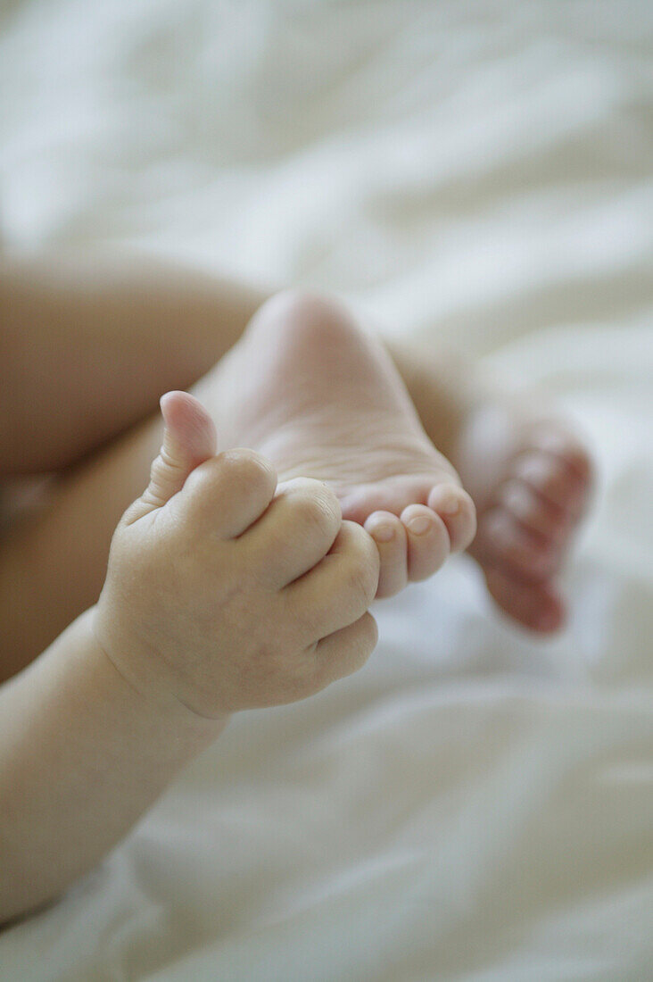 Babyhände spielen mit Füssen
