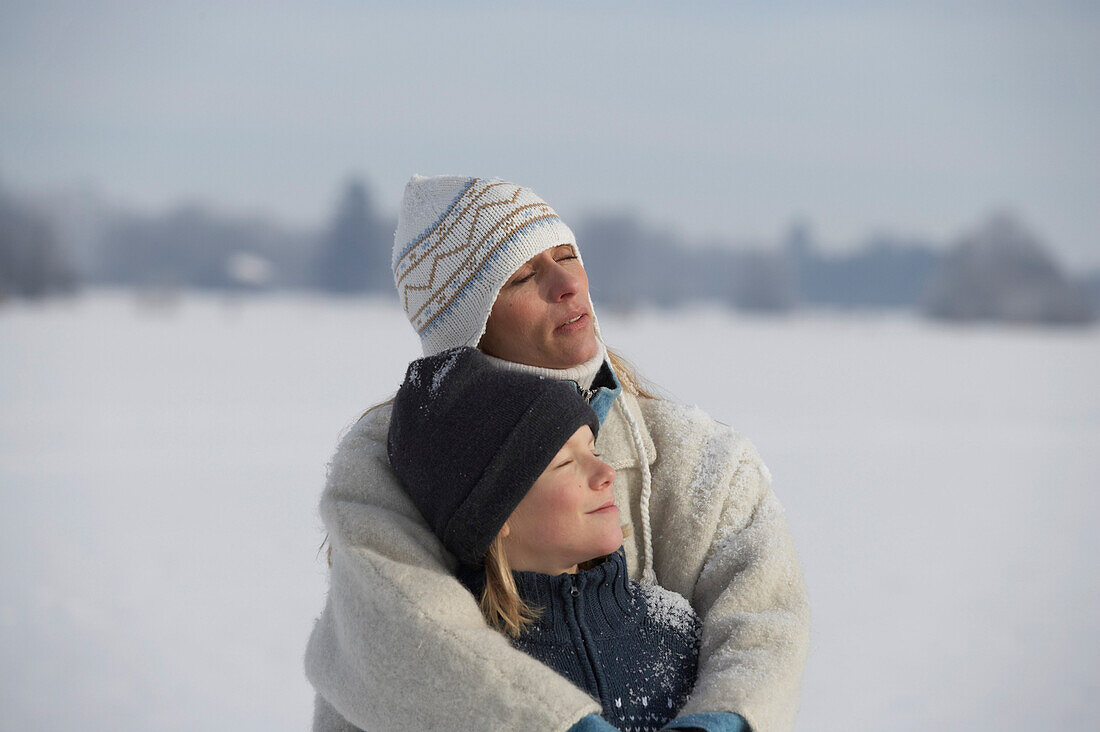 Mother hugging her son, winter scenery