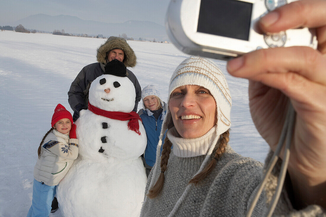 Familie und Schneemann werden von der Mutter fotografiert