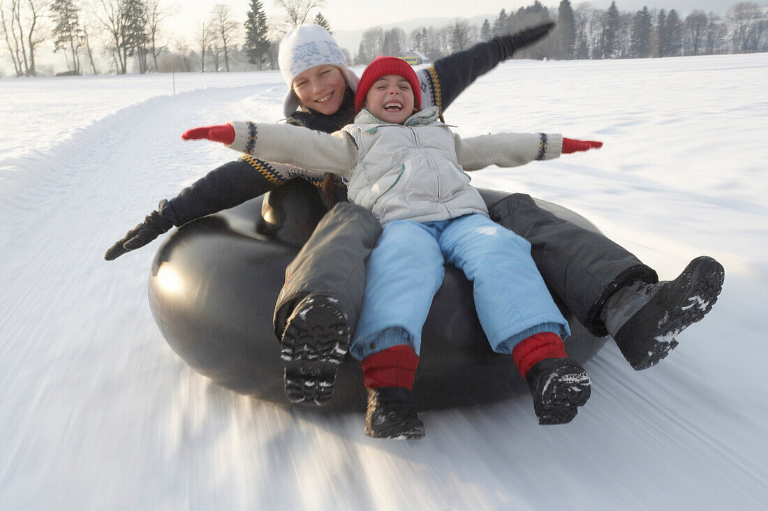 Girl and boy snowtubing