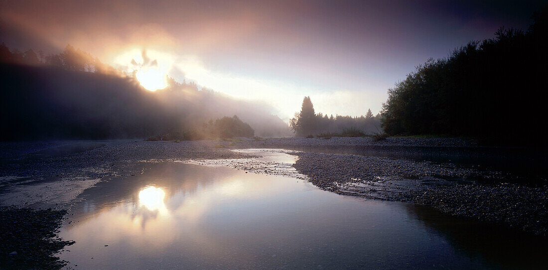 Sun's rays filtering through storm clouds onto river, River Lech, Upper Bavaria, Germany