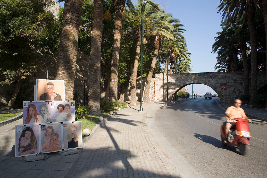 Paintings of a street performer at an avenue with palms near a bridge, Kos-Town, Kos, Greece