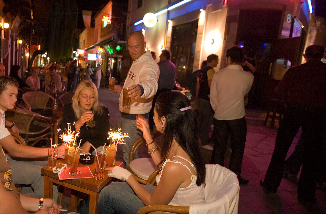 Waiter serving drinks in an open-air bar at night, Kos-Town, Kos, Greece