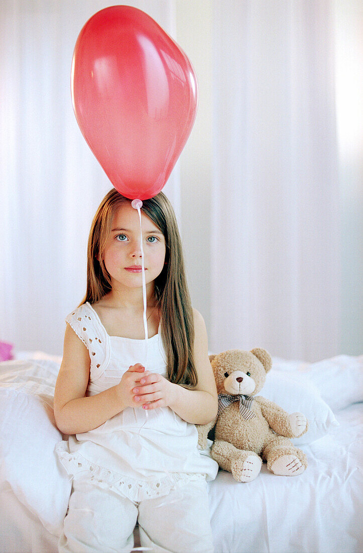 Mädchen spielt mit roten Luftballon