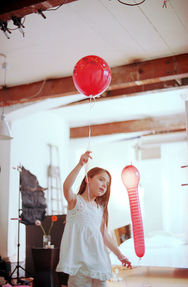 Mädchen tanzt mit roten Luftballons