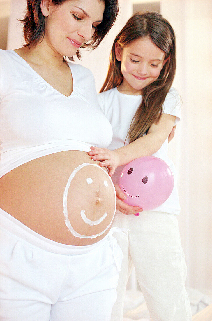 Pregnant woman with happy face on stomach