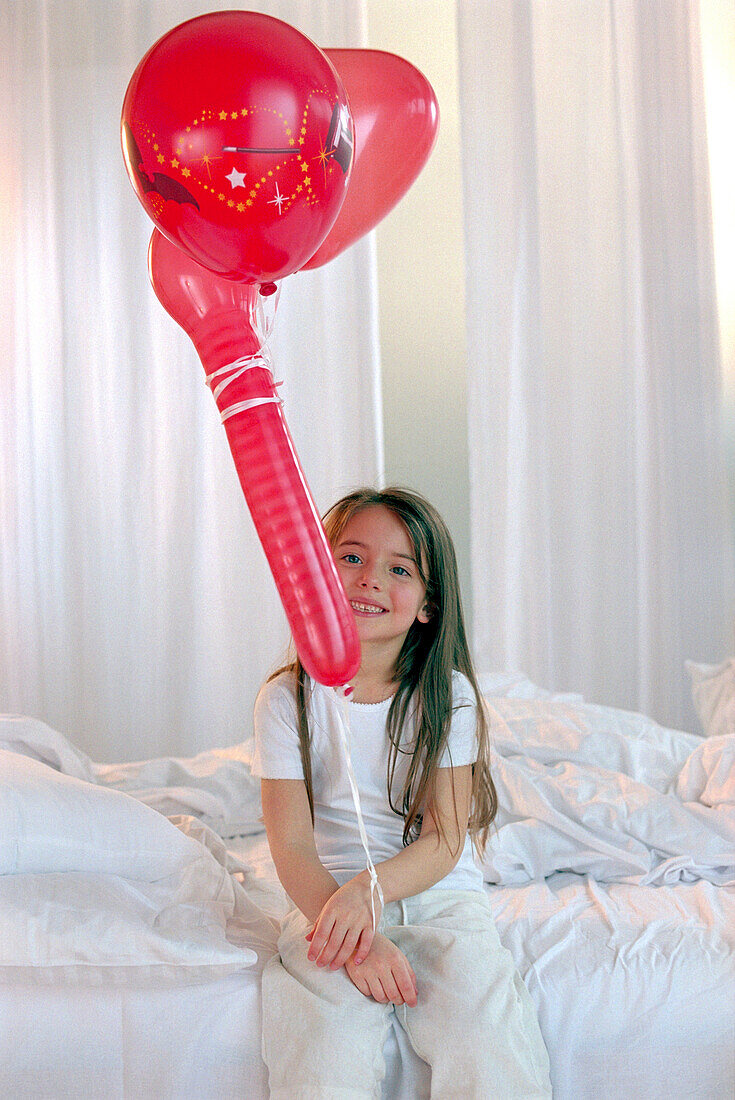 Mädchen spielt mit roten Luftballons