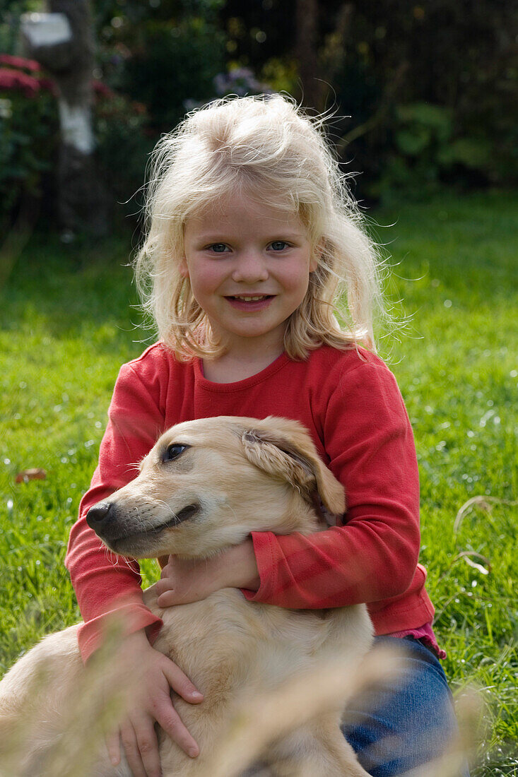 Blondes Mädchen in Garten mit Hund Golden Retriever