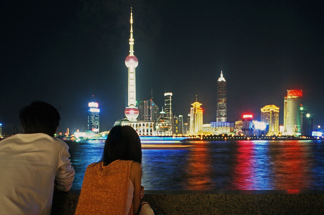 Paar schaut über den Huangpu auf die Skyline Shanghais, China
