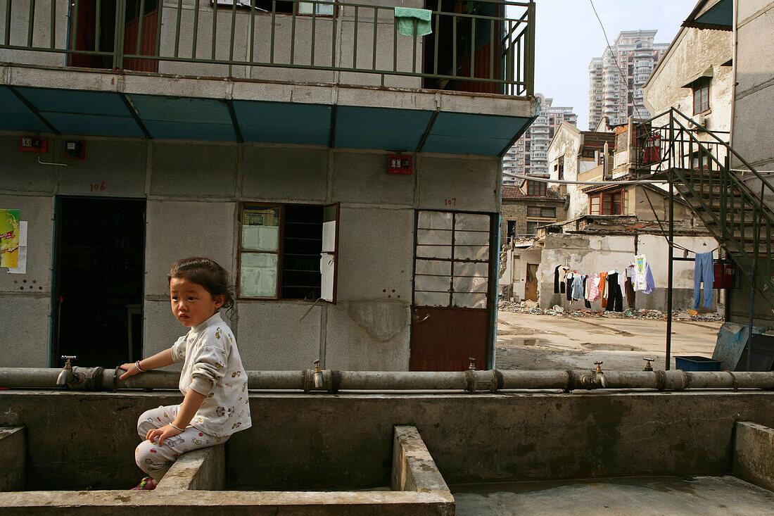 child at public water trough in demolished Lao Xi Men, Shanghai, China