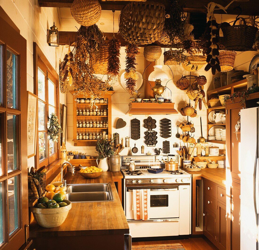 A country house kitchen with baskets, dried chilli peppers and corn cobs hanging from the ceiling, 