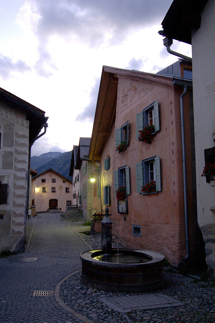 Brunnen in einer menschenleeren Strasse am Abend, Guarda, Graubünden, Schweiz