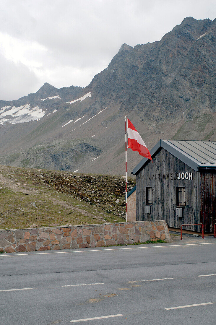 Wooden house with flag at mountain pass Timmelsjoch, Tyrol, Austria