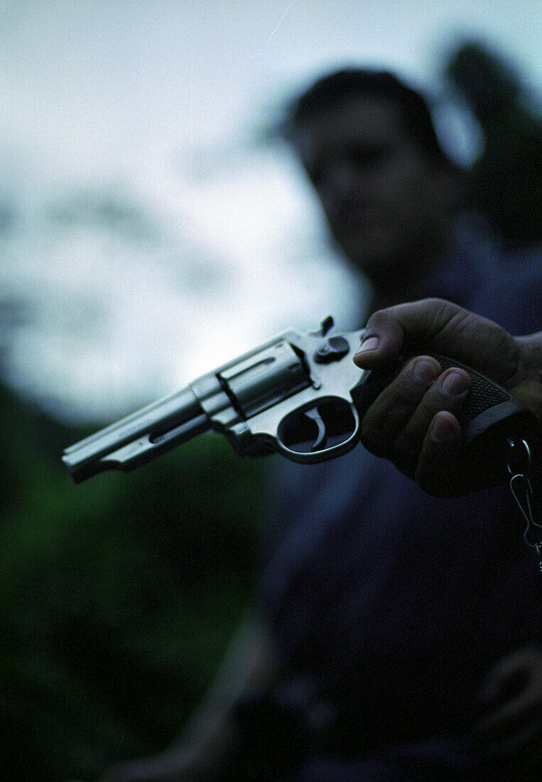 Hand holding a gun, group of people in background