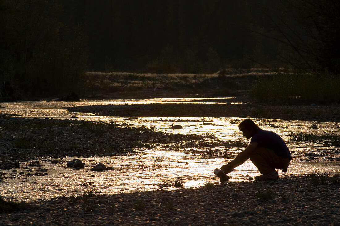 Man doing the washing up at a creek, Mackenzie Mountains, Canada