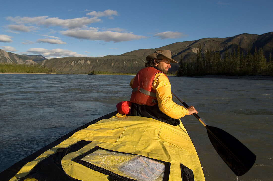 Mann beim paddeln am Nahanni Fluss blickt zurueck, Nordwestterritorien, Kanada