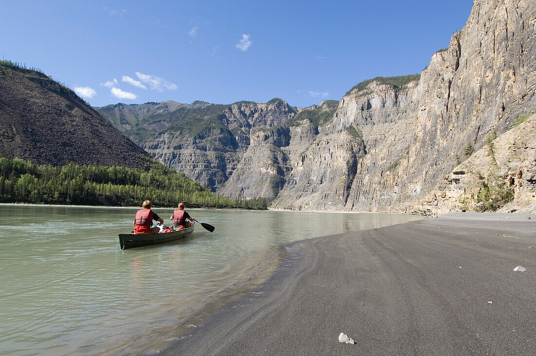 People in a canoe paddling through a canyon of the South Nahanni River, Northwest-Territories, Canada