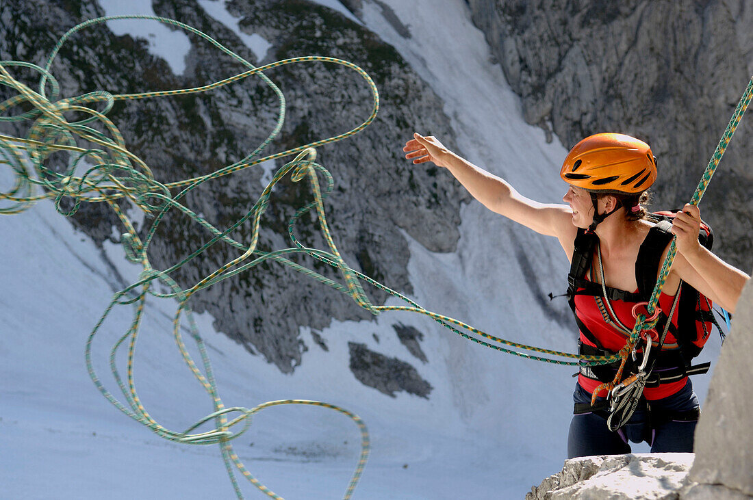 Female climber throwing rope during abseiling from Wilder Kaiser, Austria