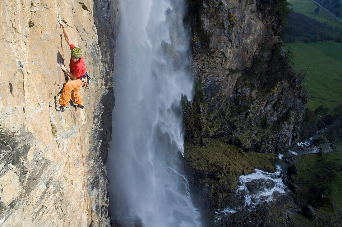 Frau klettert an eine Felswand bei einem Wasserfall, Gelber Wahn 7b+, Fallbachtal, Kärnten, Österreich