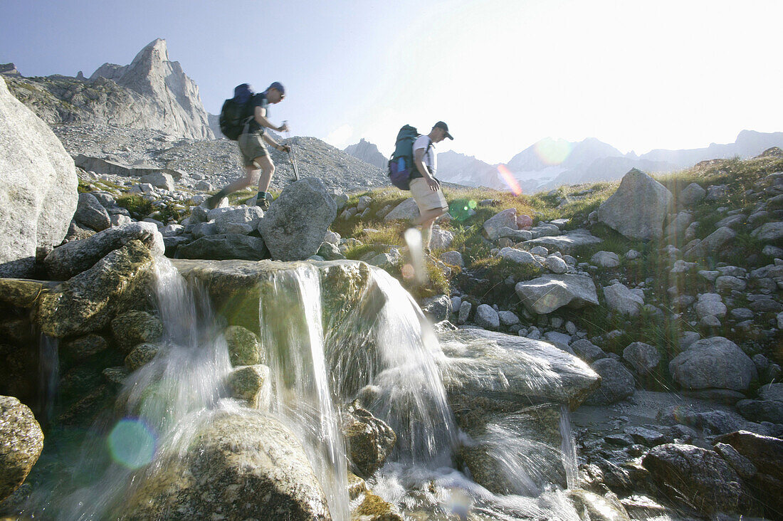 Young men walking on mountain path, near passo camerozzo,Sentiero  Roma, cengalo in back,  Bregaglia Mountains, Italy