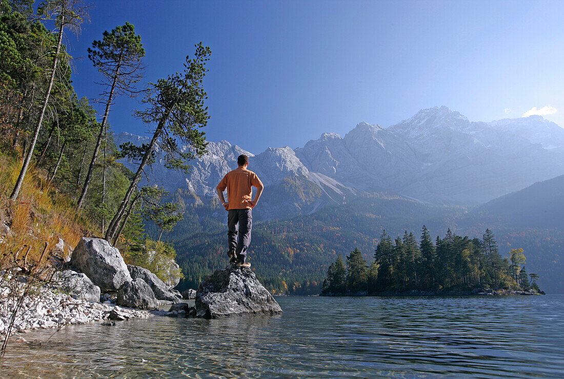 Man on shore of alpine lake,lake eibsee, Zugspitze in back, Bavaria Germany