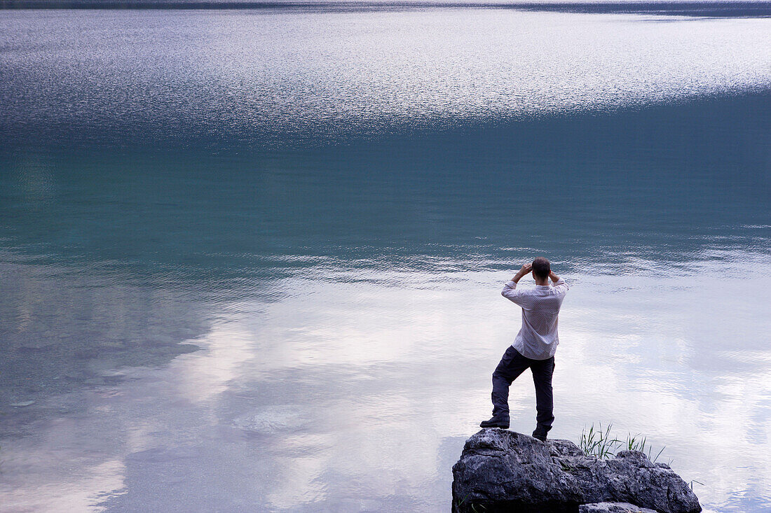 Man looking with binocular over Lake, Eibsee, Zugspitze in backround, Bavaria Germany