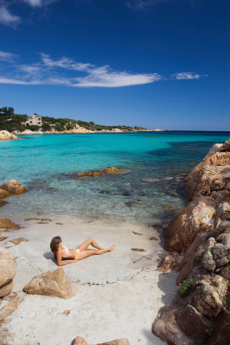 Woman sunbathing at Spiaggia Capriccioli, Costa Smeralda, Sardinia, Italy