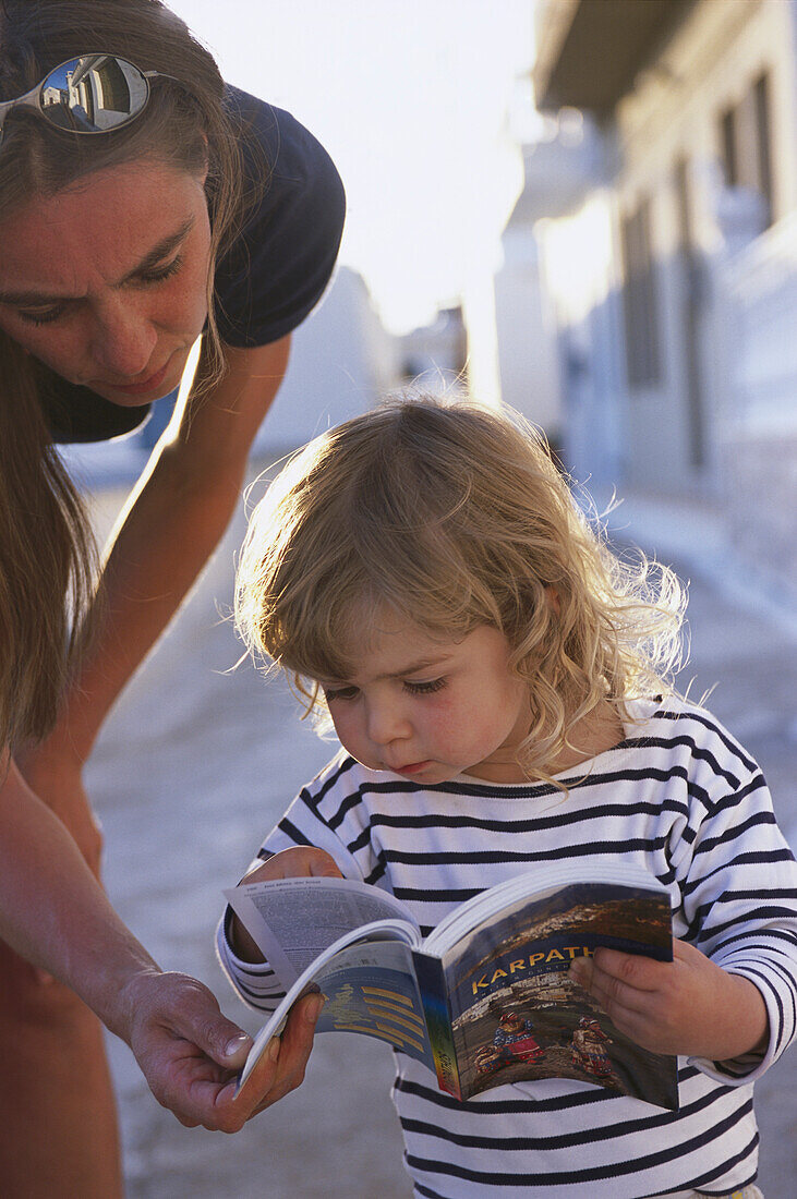 Mother and little daughter looking in guidebook, Karpathos, Dodecanese Islands, Greece