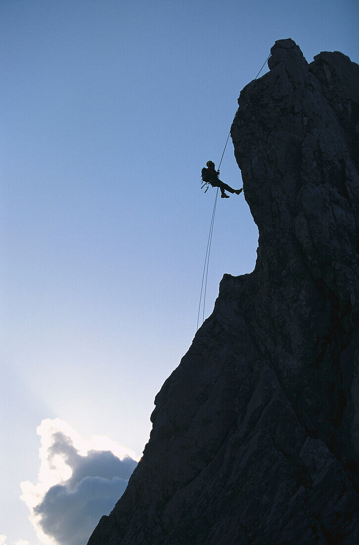 Silhouette of man climbing rock face, side view, Alpspitze, Bavaria, Germany