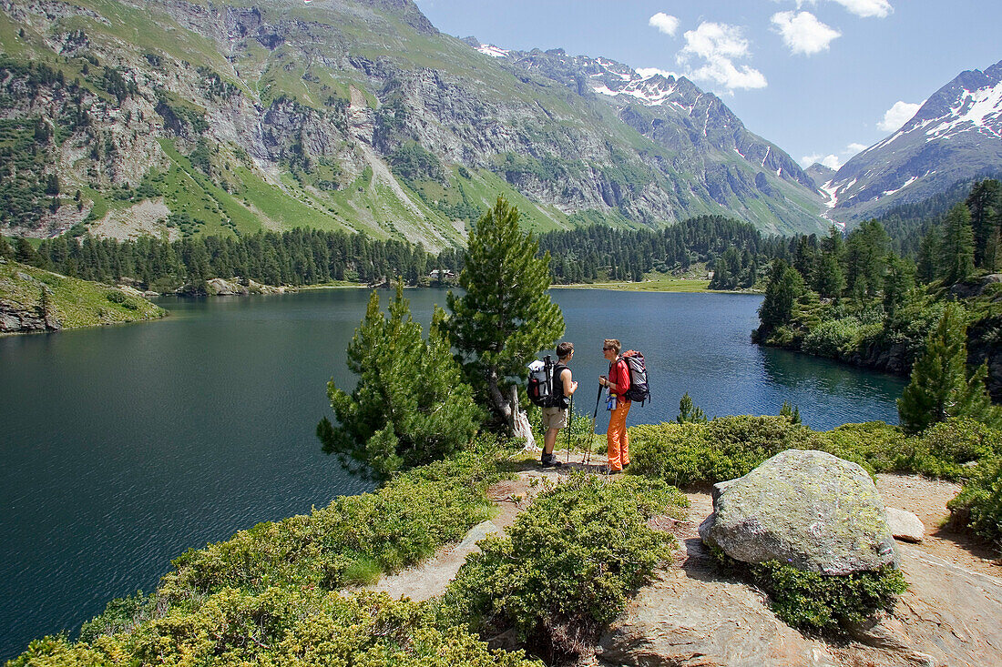 Two hiking women taking a rest in front of a mountain lake, Laegh Cavloc, Cavloc Lake, Forno, Bergell, Graubuenden, Grisons, Switzerland