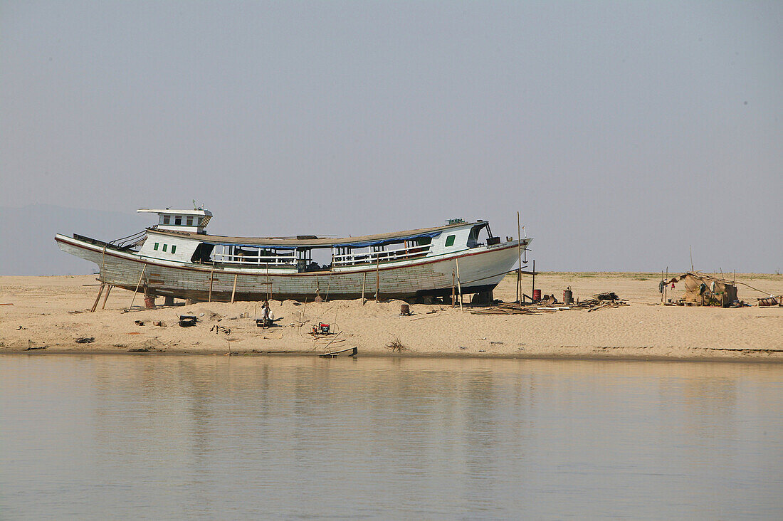 Riverside scenery, boat in dry dock, Irrawaddy river scene old boat being repaired on riverbank Boot am Ufer der Ayeyarwady Fluss