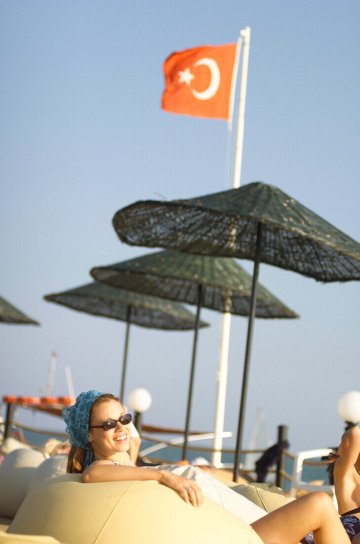 Lächelnde Frau sitzt am Strand, Türkei