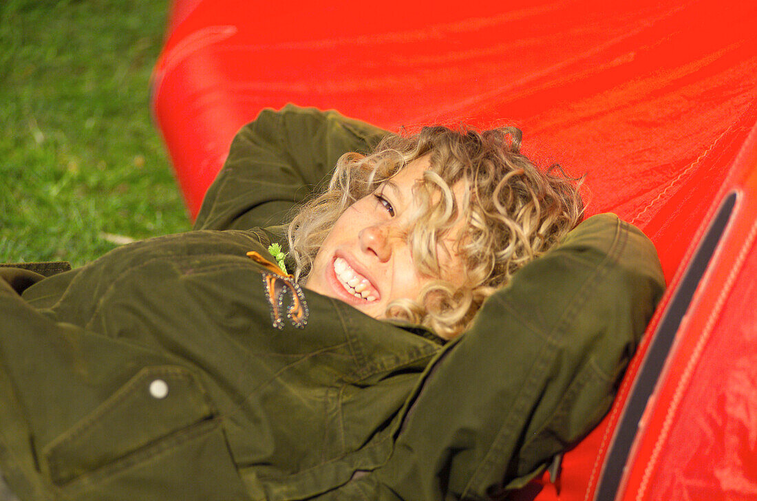 Young woman with a blond curly hair lying in the sun and smiling