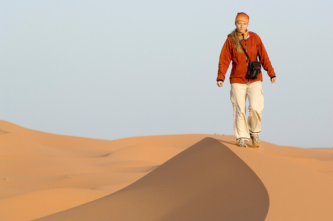 Woman walking on sand dune, Erg Chebbi, Morocco