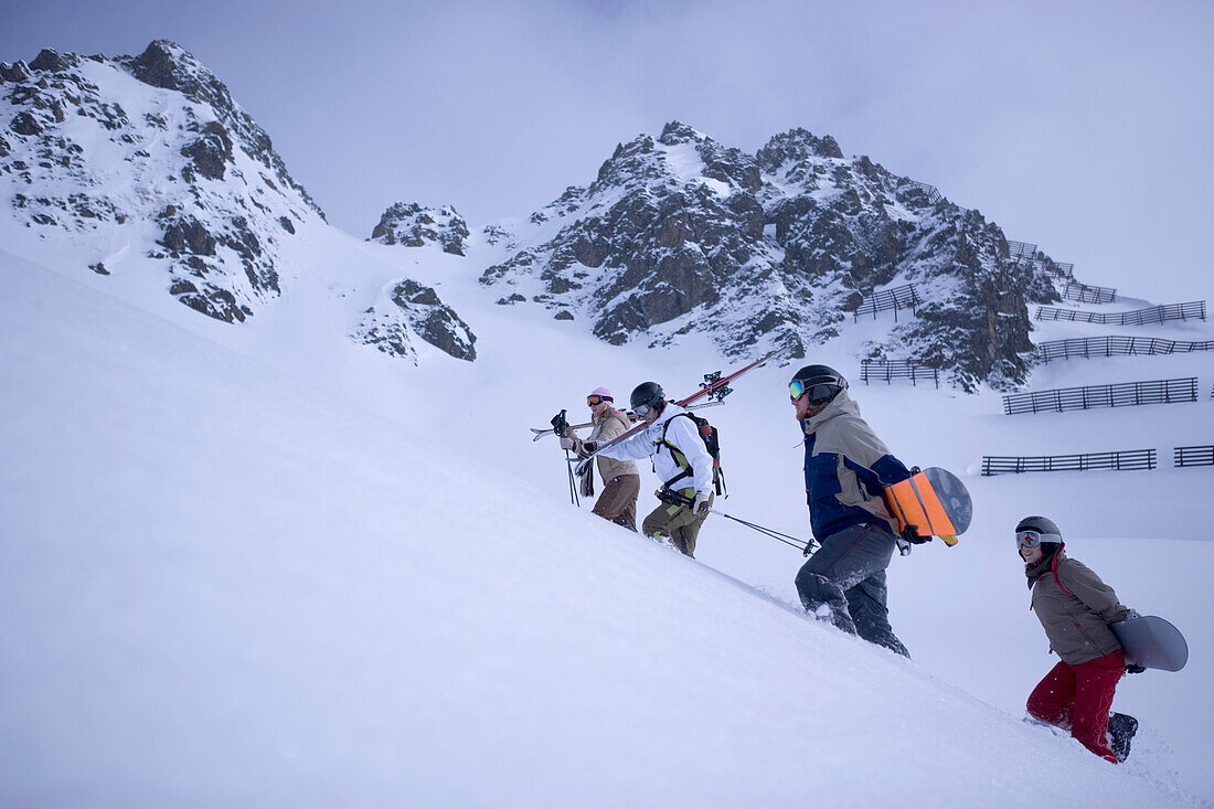 Vier Personen tragen Snowboards oder Skier, Kühtai, Tirol, Österreich