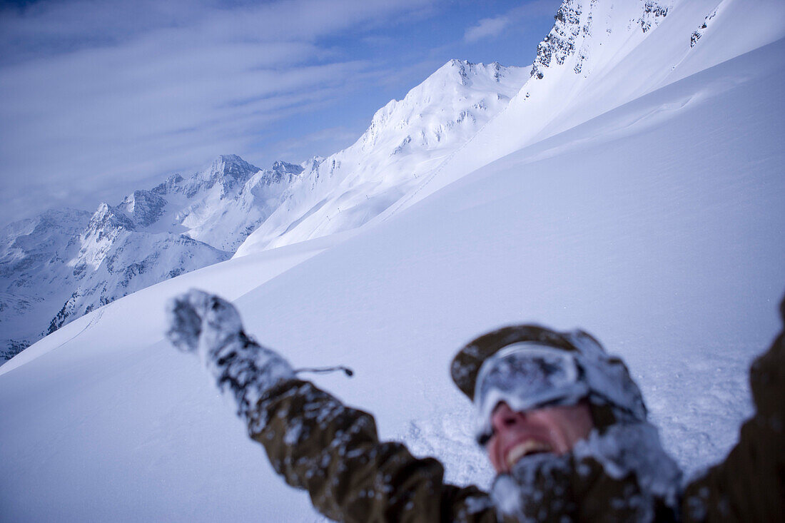 Mann schneebedeckt reißt die Arme in die Höhe, Kühtai, Tirol, Österreich