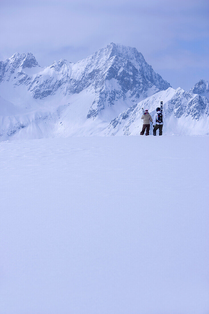 Two skier standing on snow hill, looking mountain panorama, Kuehtai, Tyrol, Austria