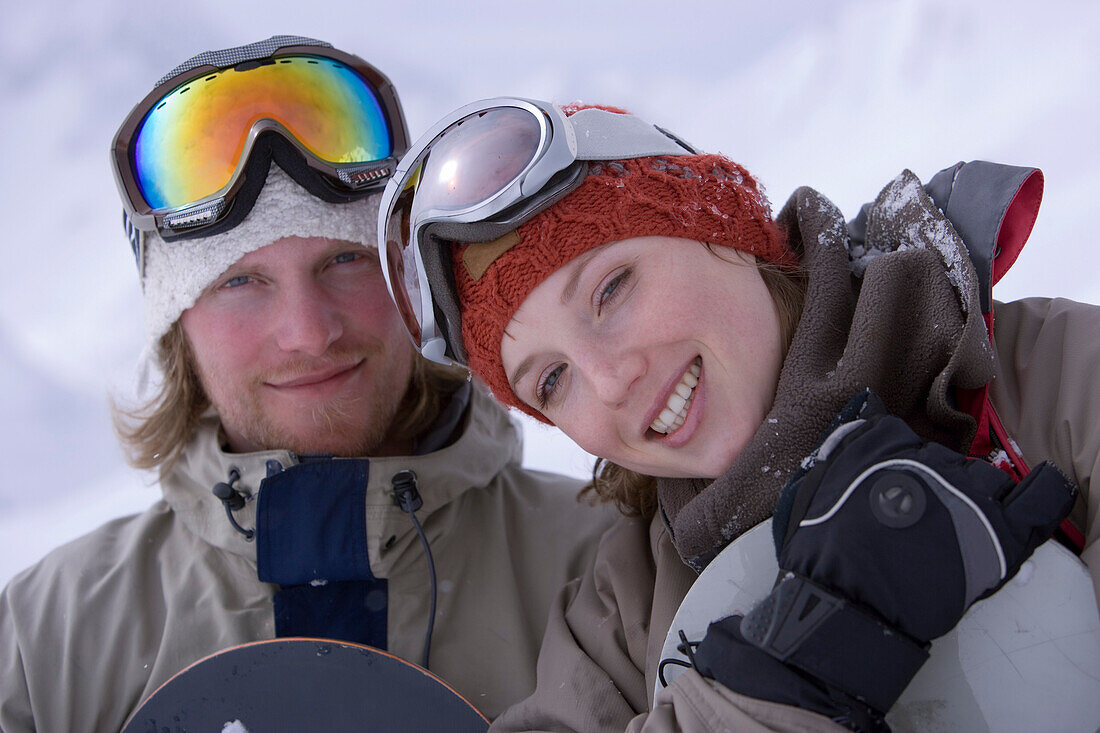 Junges Paar hält Snowboards, Kühtai, Tirol, Österreich