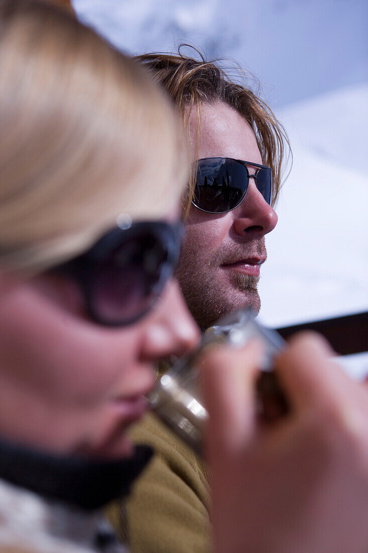 Couple sunbathing on terrace of ski lodge, drinking tea, Kuehtai, Tyrol, Austria