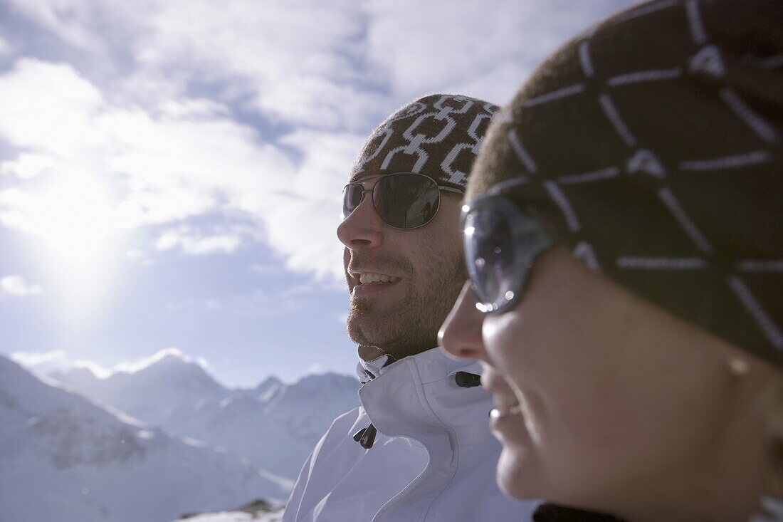 Junges Paar steht an der Skipiste, beide tragen Sonnenbrillen, Kühtai, Tirol, Österreich