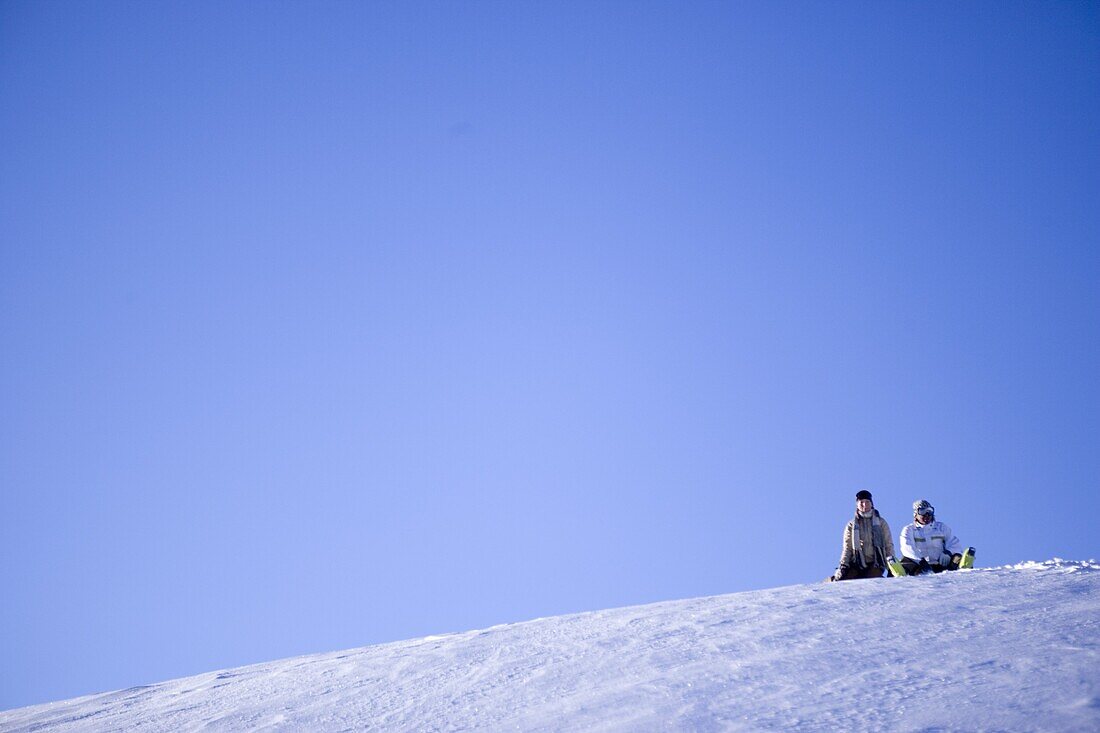 Young couple sitting near slope on snowcoverd mountain, Kuehtai, Tyrol, Austria