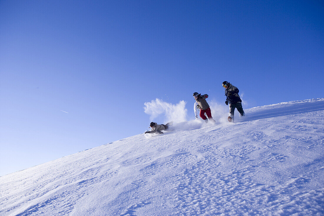 Gruppe junger Menschen laufen im Schnee den Berg hinunter, Kühtai, Tirol, Österreich