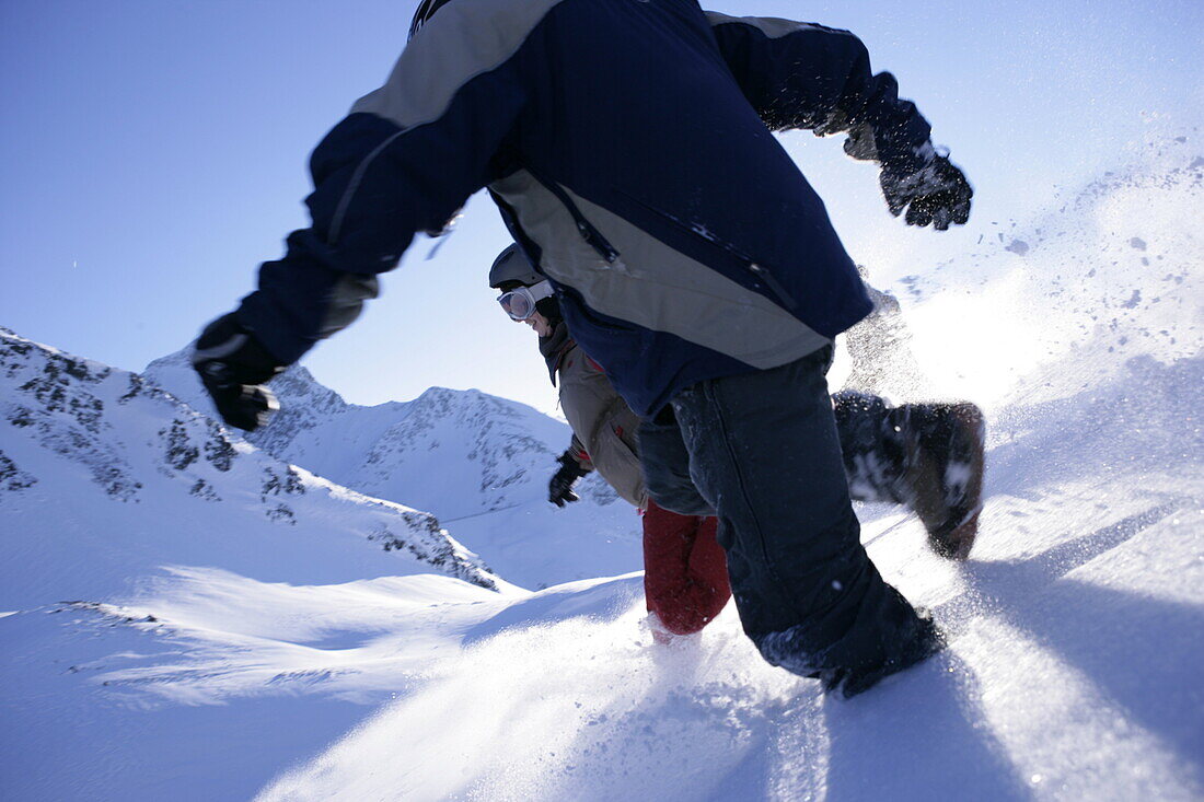 Group of young people running downhill snowcapped mountain, Kuehtai, Tyrol, Austria