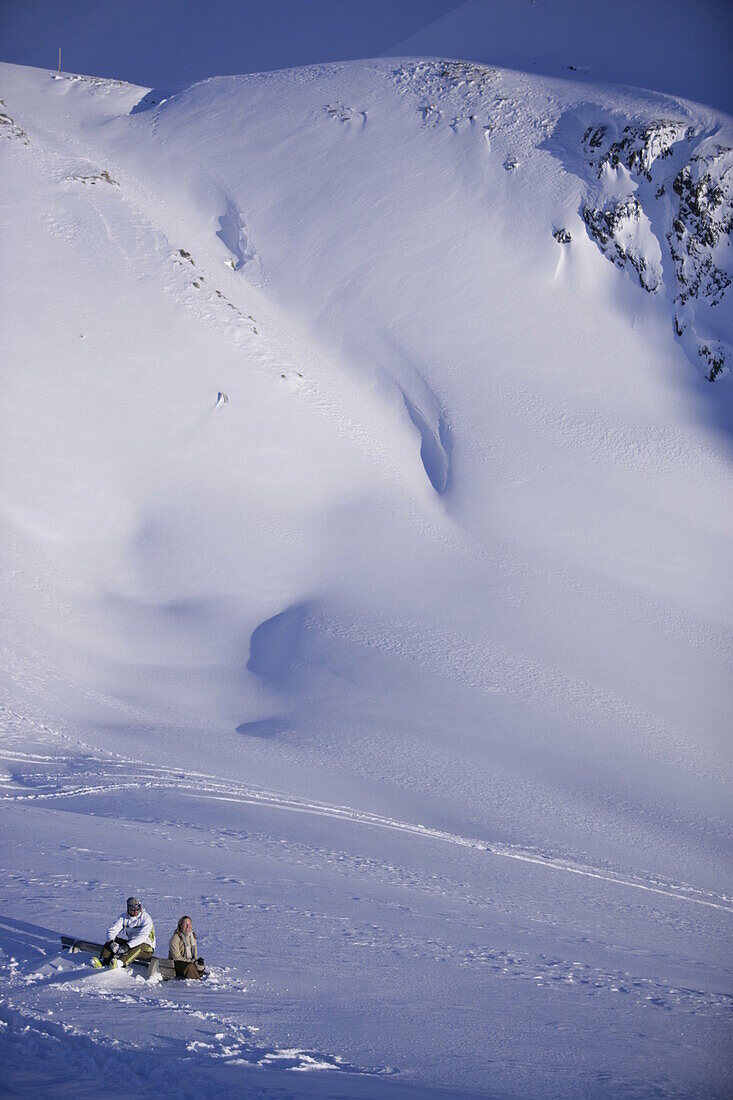 Junges Paar sitzt neben der Skipiste, Kühtai, Tirol, Österreich