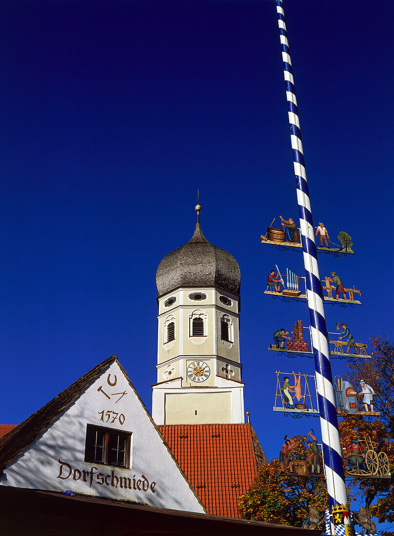 Low angle view a maypole and church of Erling, Upper Bavaria, Germany