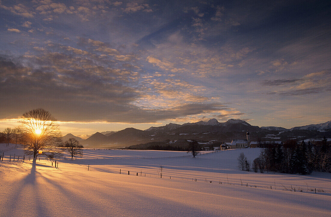 Wendelsteinmassiv mit Kirche in Wilparting bei Sonnenaufgang mit dramatischer Bewölkung, Bayerische Voralpen, Oberbayern, Deutschland