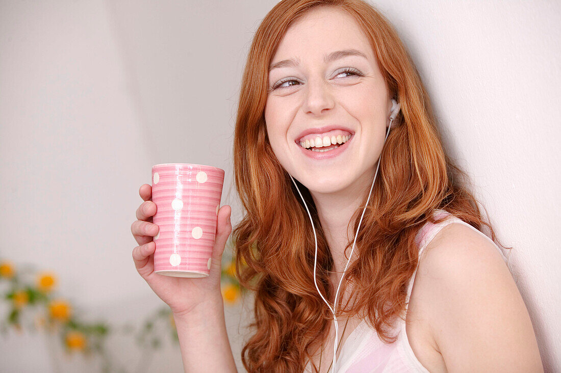 Junge Frau lächelt mit Tasse in der Hand