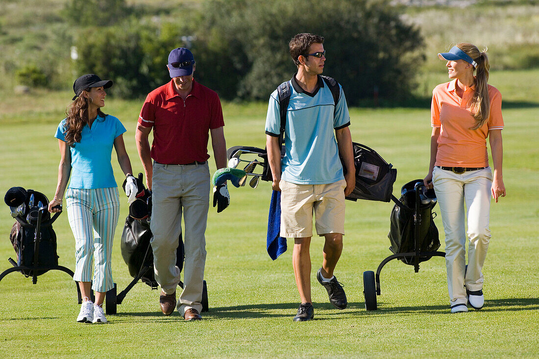 Group of people walking on golf course pulling golf bag on wheels, Apulia, Italy