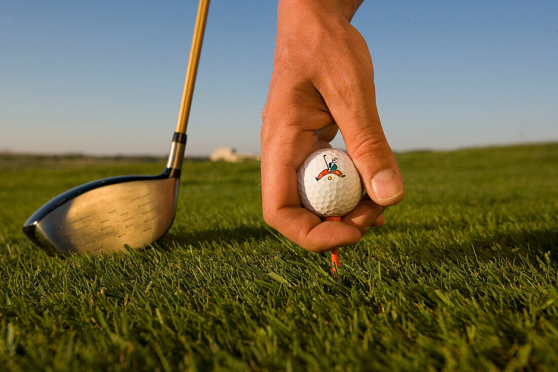 Golf, man placing golf ball on tee