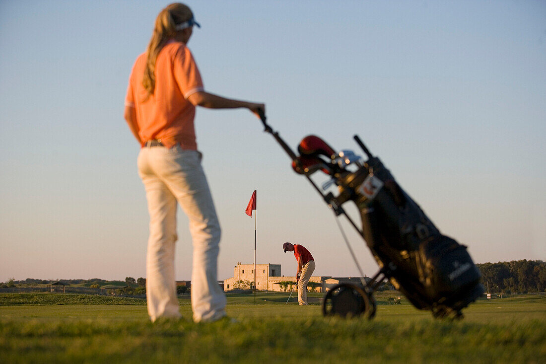 Golfer beim Einlochen, Frau schaut zu, Apulien, Italien